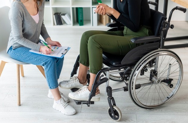 Un handicapé qui discute avec une dame assise sur une chaise